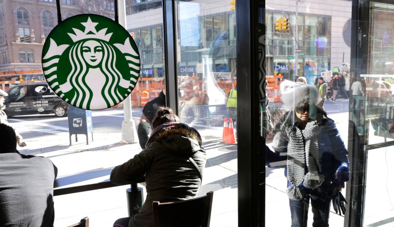A woman walks into a Starbucks in New York City as several people sit near the front door.