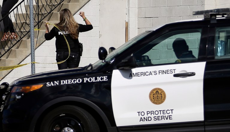 San Diego police officers assist a couple as they evacuate a building in San Diego on Wednesday, Nov. 4, 2015. A man with a high-powered gun was firing sporadically inside a San Diego apartment complex, causing the city's nearby airport to stop planes from landing, authorities said.