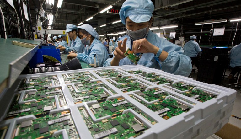 In this Tuesday, Nov. 10, 2015, photo, a worker assembles electronic devices at an Alco Electronics factory in Houjie Town, Dongguan City, in the Guangdong province of China.