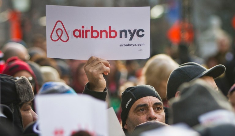 FILE - In this Jan. 20, 2015, file photo, supporters of Airbnb hold a rally outside City Hall in New York. The New York state Senate has cleared a bill that would ban companies like Airbnb from advertising apartments from short-term rentals in New York.