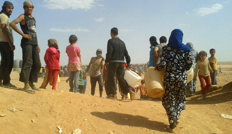 In this June 23, 2016, file photo, Syrian refugees gather for water at the Rukban refugee camp in Jordan's northeast border with Syria.