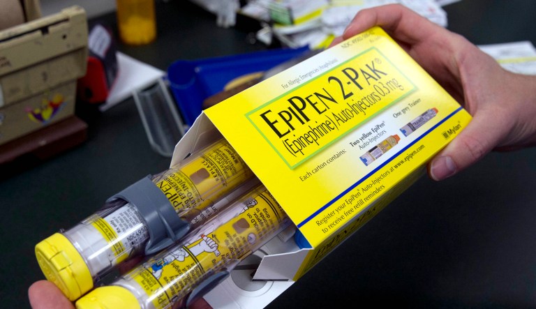 A pharmacist holds a package of EpiPen epinephrine auto-injectors.