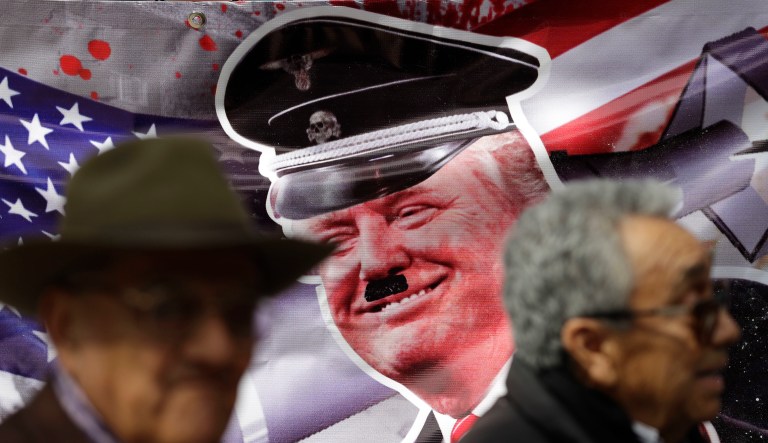 Jose Luis Gonzalez Meza, right, one of the lawyers for drug lord Joaquin "El Chapo" Guzman, and Jose Puente Leon stand in front of a banner portraying U.S. President-elect Donald Trump with a Hitler moustache, as they stage a two-person protest in front of the U.S. embassy in Mexico City, Monday, Nov. 14, 2016. They said they were protesting in solidarity with Mexicans in the U.S. 