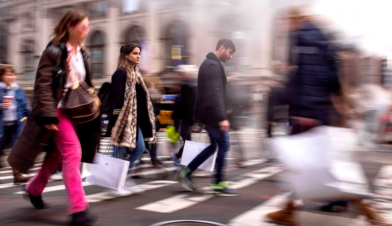 Shoppers carry their purchases as they walk though the steam coming from the underground along Fifth Avenue on Black Friday in New York.