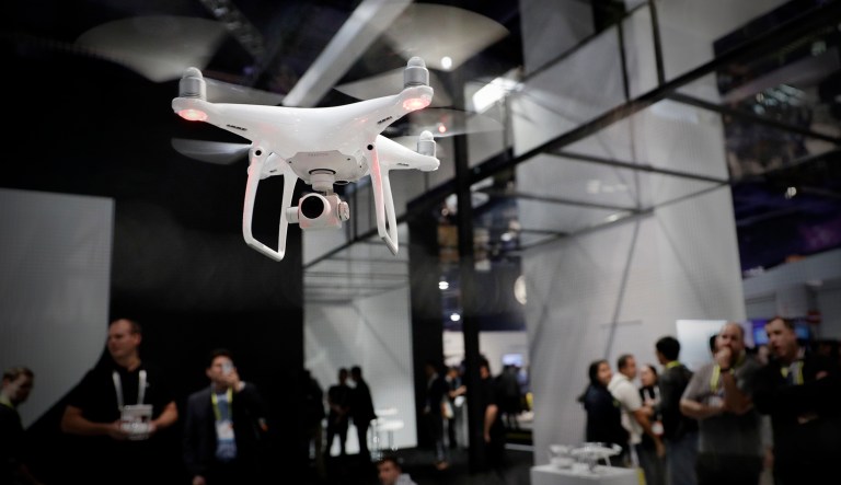 People watch a flying demonstration of a drone at the DJI booth at CES International in Las Vegas. 