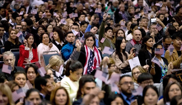 People wave U.S. flags during a naturalization ceremony at the Los Angeles Convention Center.