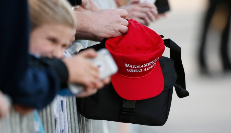 A supporter holding a "Make America Great Again" hat waits to greet President Trump when he arrives on Air Force One in West Palm Beach, Fla., on Feb. 10, 2017.