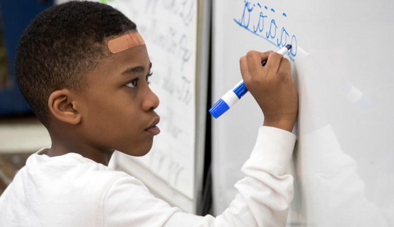 In this Wednesday, March 1, 2017, photo, a third-grader practices his cursive handwriting at P.S. 166 in the Queens borough of New York. Cursive writing is looping back into style in schools. Last fall, the 1.1 million-student New York City schools encouraged the teaching of cursive to students as young as the third grade.