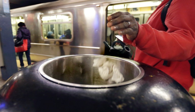 A subway passenger tosses trash in a Chambers Street platform receptacle, in New York, Thursday, March 30, 2017. Faced with the problem of too much litter and too many rats in their subway stations, New York City transit officials began an unusual social experiment a few years ago. They removed trash bins entirely from select stations, figuring it would deter people from bringing garbage into the subway in the first place. This week, they pulled the plug on the program after reluctantly concluding that it was a failure.