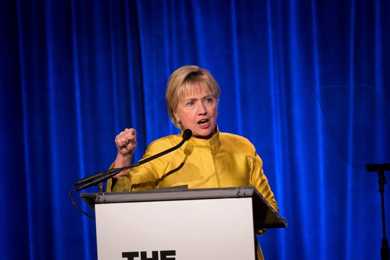 Former Secretary of State Hillary Clinton makes a speech in front of a podium.
