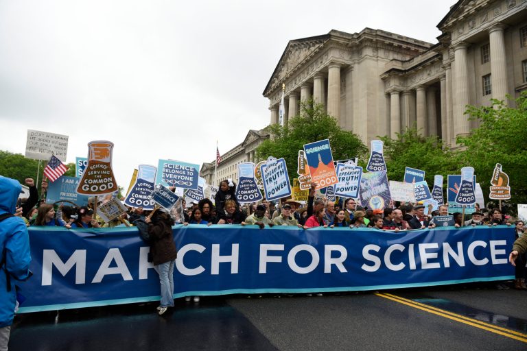 People carry a March for Science banner and signs as they pass the U.S. Environmental Protection Agency during the March For Science in Washington on April 22, 2017.