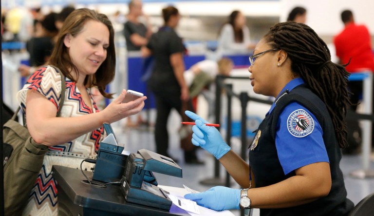 A Transportation Security Administration officer looks on as a traveler scans her boarding pass on her phone, May 2, 2017, at Miami International Airport in Miami.