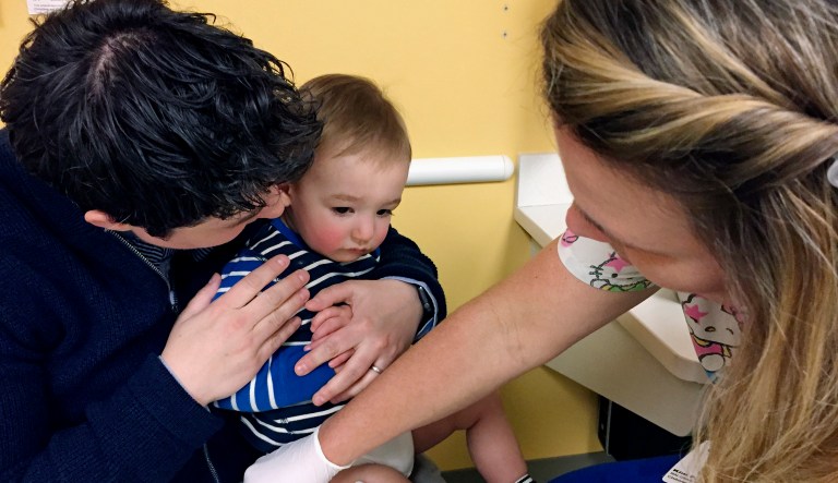 15-month-old August Goepferd received the measles, mumps and rubella booster shot at a clinic at Children's Minnesota in Minneapolis. August sat on the lap of his mom, Dr. Angela Geopferd, as registered nurse Kim Flaata administered the shot. 