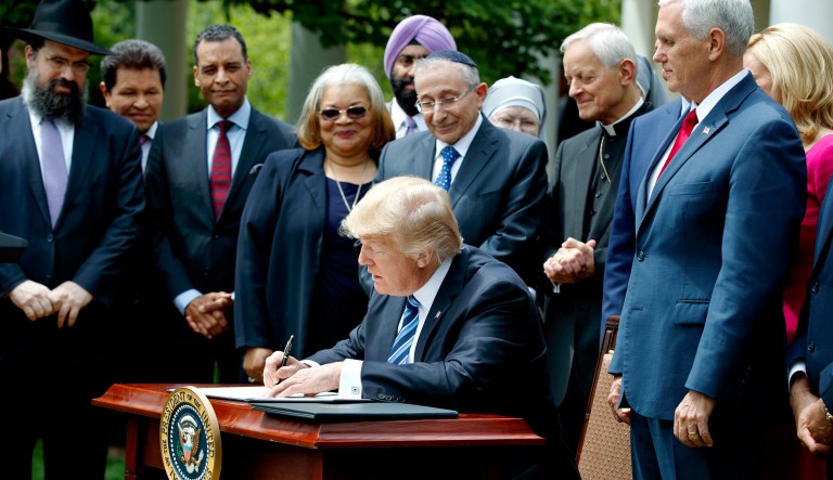In this May 4, 2017 file photo, President Trump signs an executive order aimed at easing an IRS rule limiting political activity for religious organizations, in the Rose Garden of the White House in Washington.