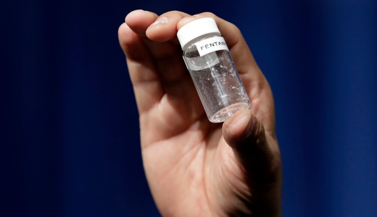 A reporter holds up an example of the amount of fentanyl that can be deadly after a news conference about deaths from fentanyl exposure. 