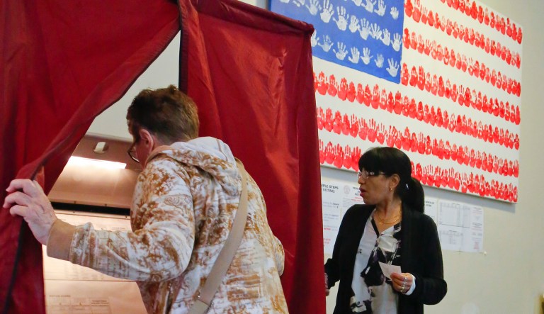 Poll station administrator Leticia Velez watches as a voter enters the booth at City Hall during primary voting for New Jersey gubernatorial candidates on June 6, 2017, in Hoboken, N.J.