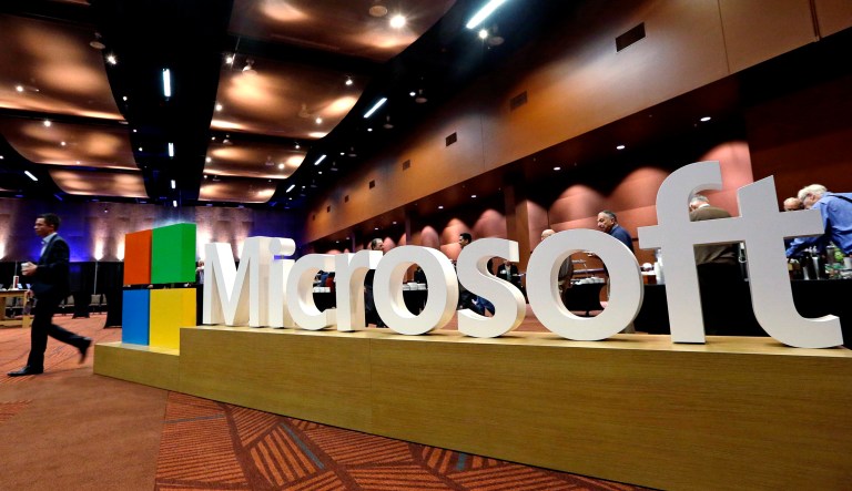 A man walks past a Microsoft sign at a meeting.