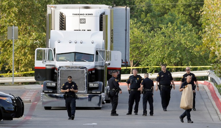 San Antonio police officers investigate the scene where eight people were found dead in a tractor-trailer loaded with at least 30 others outside a Walmart store in stifling summer heat in what police are calling a horrific human trafficking case in San Antonio.