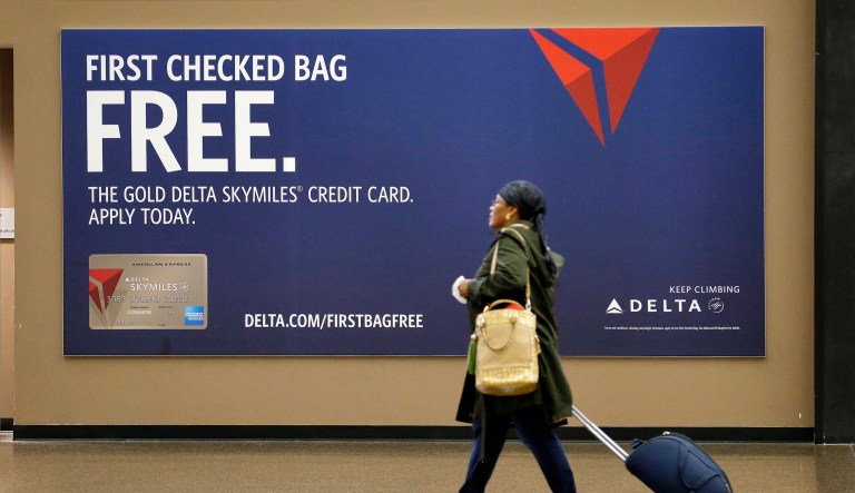 A traveler walks past a sign advertising a Delta Air Lines credit card at Seattle-Tacoma International Airport in SeaTac, Wash., on March 24, 2015.