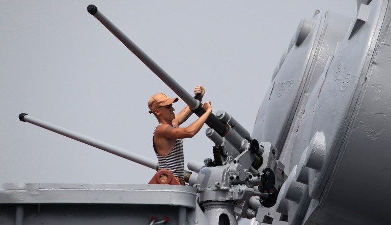 A Russian Navy crew member cleans the guns of the Admiral Vinogradov, a Russian anti-submarine ship, as its arrives at the south harbor in Manila, Philippines, on Friday, Oct. 20, 2017. Three Russian navy ships arrived in the Philippines on Friday and two others are coming to deliver donated military equipment in the country's third naval visit under President Rodrigo Duterte, who has vowed to diversify the country's ties away from the United States and toward China and Russia.