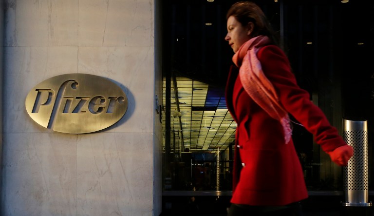 FILE - In this Monday, Nov. 23, 2015, file photo, a woman passes Pfizer's world headquarters in New York. Pfizer Inc. reports earnings Tuesday, Oct. 31, 2017. 