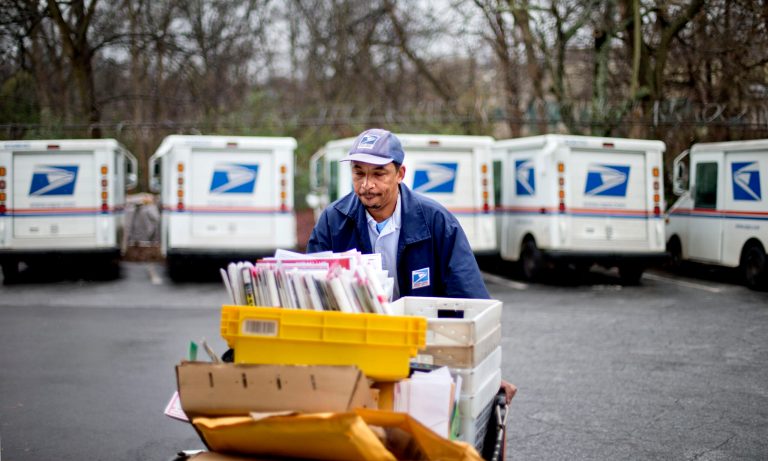 In this Feb. 7, 2013 file photo, a U.S. Postal Service letter carrier gathers mail to load into his truck before making his delivery run in the East Atlanta neighborhood in Atlanta. As consumers demand ever-quicker and convenient package delivery, the U.S. Postal Service wants to boost its business this holiday season by offering what few e-commerce retailers can provide: cheap next-day service with packages delivered Sundays to your home. 