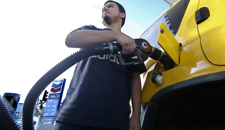 In this photo taken Monday, Oct. 30, 2017, Cristian Rodriguez fuels his vehicle, in Sacramento, Calif.