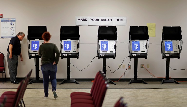An investigator with the Georgia secretary of state office, left, takes a look at a new voting machine being tested at a polling site. 