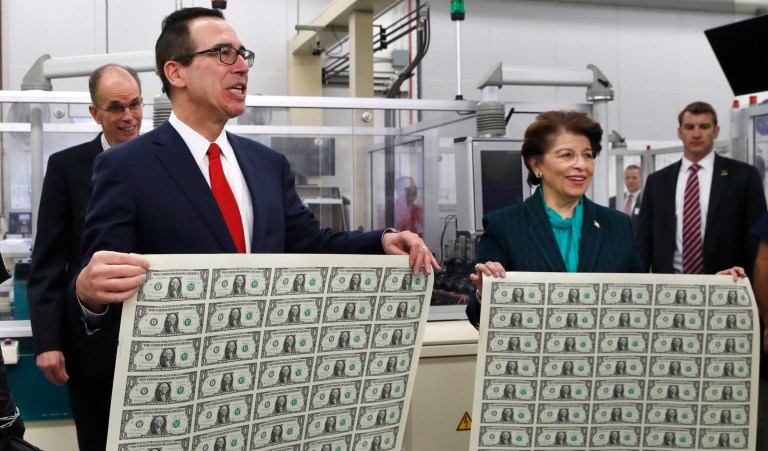 Treasury Secretary Steven Mnuchin, with his wife Louise Linton, at far left, and U.S. Treasurer Jovita Carranza, right, hold up sheets of new $1 bills, the first currency notes bearing Mnuchin and Carranza's signatures, Wednesday, Nov. 15, 2017, at the Bureau of Engraving and Printing in Washington. 