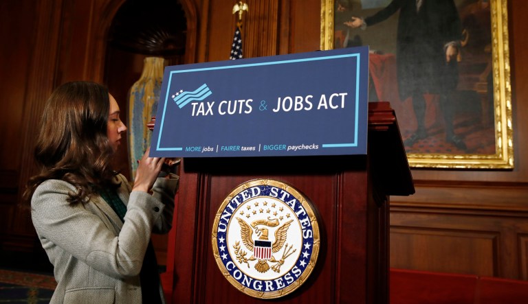 A House staff member affixes a sign that says "Tax Cuts and Jobs Act" ahead of a gathering of House Republicans making statements to the media following a vote on the GOP tax overhaul bill, Thursday, Nov. 16, 2017, on Capitol Hill in Washington. (AP Photo/Jacquelyn Martin)