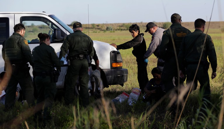In this Aug. 11, 2017, photo, immigrants suspected of crossing into the United States illegally along the Rio Grande near Granjeno, Texas, are held by U.S. Customs and Border Patrol agents.