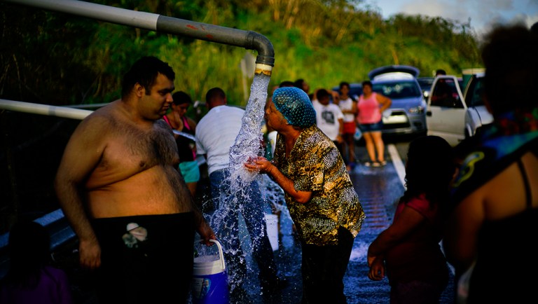 People who lost access to water in the wake of Hurricane Maria gather at pipes carrying water from a mountain creek, on the side of the road in Utuado, Puerto Rico.