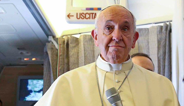Pope Francis talks to journalists onboard a plane.