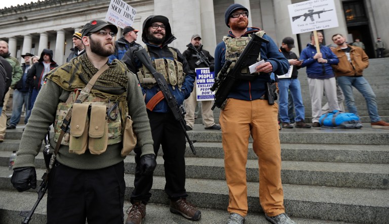 In this Jan. 12, 2018 photo, Ian Stobie, left, Jake Garza, second from left, and Ben Garrison, third from left, and all of Puyallup, Wash., open-carry their guns on the steps of the Legislative Building as they attend a gun rights rally, Friday, Jan. 12, 2018, at the Capitol in Olympia, Wash. A Washington state Legislature Senate committee held a public hearing Monday, Jan. 15, on several bills related to guns, including measures to prohibit high-capacity magazines and to ban so-called bump stocks, trigger modification devices designed to increase the rate of fire of a firearm. 