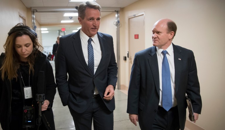 Sen. Jeff Flake, center, R-Ariz., speaks with Sen. Chris Coons, D-Del., while returning to the Capitol after they worked with a bipartisan group of moderate senators to find a way to reopen the government on Day 2 of the federal shutdown, in Washington on Sunday, Jan. 21, 2018.