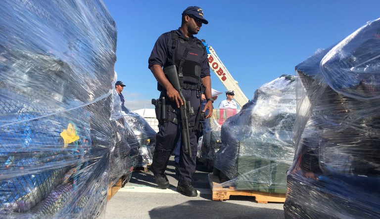 An armed guard walks by bundles of cocaine aboard the U.S. Coast Guard Cutter Stratton in San Diego on Thursday, Jan. 25, 2018. The Coast Guard seized around 47,000 pounds of cocaine in the Pacific since November. The drugs are worth more than $721 million. 