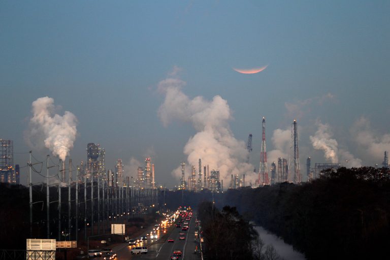 A supermoon undergoes a partial eclipse as it sets beyond gas refineries at sunrise in St. Charles Parish, La.