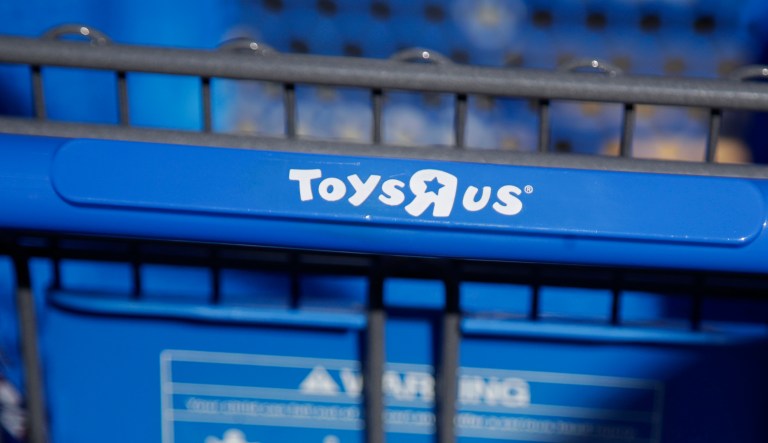 FILE- In this Jan. 24, 2018, file photo, a lone shopping cart sits in a kiosk on the parking lot of a Toys R Us store in Paramus, N.J. Toys R Us CEO David Brandon told employees Wednesday, March 14, 2018, that the company's plan is to liquidate all of its U.S. stores, according to an audio recording of the meeting obtained by The Associated Press. (AP Photo/Julio Cortez, File)