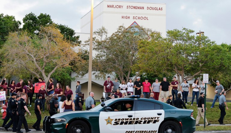A police car drives by Marjory Stoneman Douglas High School in Parkland, Fla. Students returned to class for the first time since a former student opened fire there with an assault weapon.