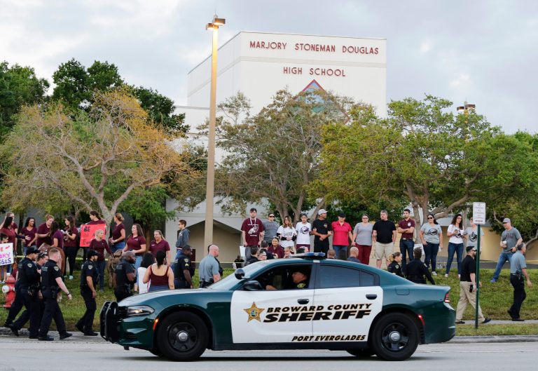 A police car drives by Marjory Stoneman Douglas High School in Parkland, Fla., where a former student opened fire and killed 17 people.