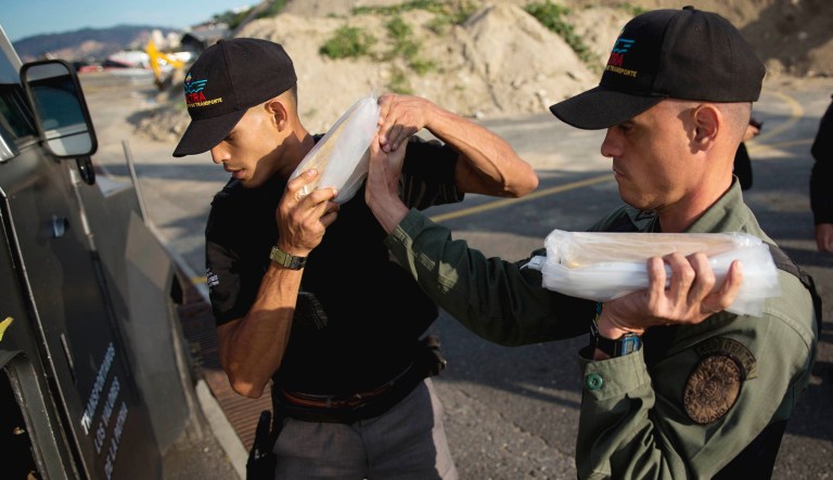 Members of a military agency that transports valuables put gold bars into an armored vehicle to be taken to Venezuela's Central Bank, at the Carlota military airport in Caracas, Venezuela.