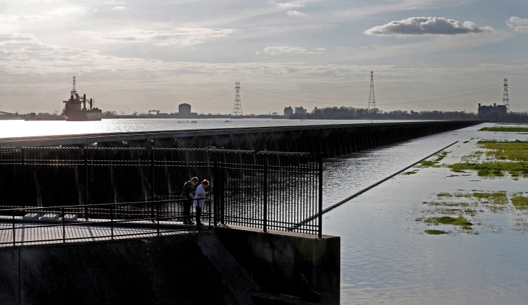 In this March 5, 2018, file photo, people look at the inside of the Bonnet Carre Spillway, as ships along the rising Mississippi River are seen on the other side of the floodgates, in Norco, La. The U.S. Army Corps of Engineers will open part of the Bonnet Carre Spillway on Thursday, March 8, 2018.