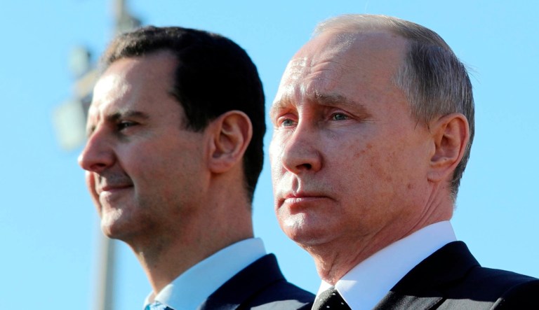 This Dec. 11, 2017 file photo shows Russian President Vladimir Putin, right, and Syrian President Bashar Assad watching troops march at the Hemeimeem air base in Syria.