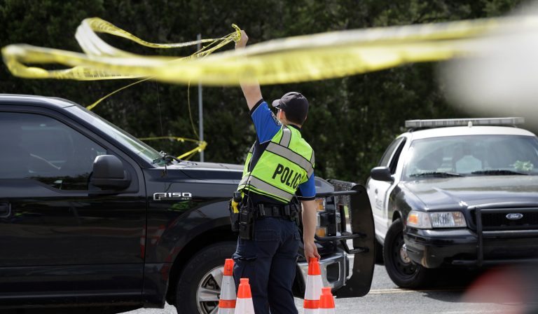 An Austin police officer raises a barrier near the site of Sunday's explosion, Monday, March 19, 2018, in Austin, Texas. Multiple people were injured in the explosion Sunday night, and police warned nearby residents to remain indoors overnight as investigators looked for possible links to other package bombings elsewhere in the city this month.