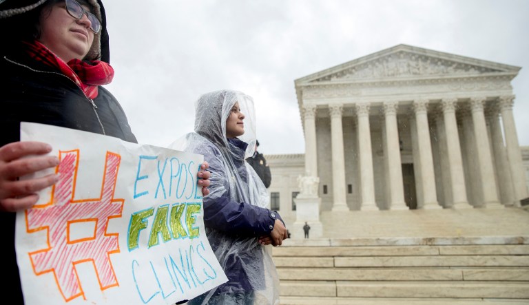 A pro-abortion rights supporter holds a sign that reads "Expose Fake Clinics" during a rally outside the Supreme Court in Washington. 