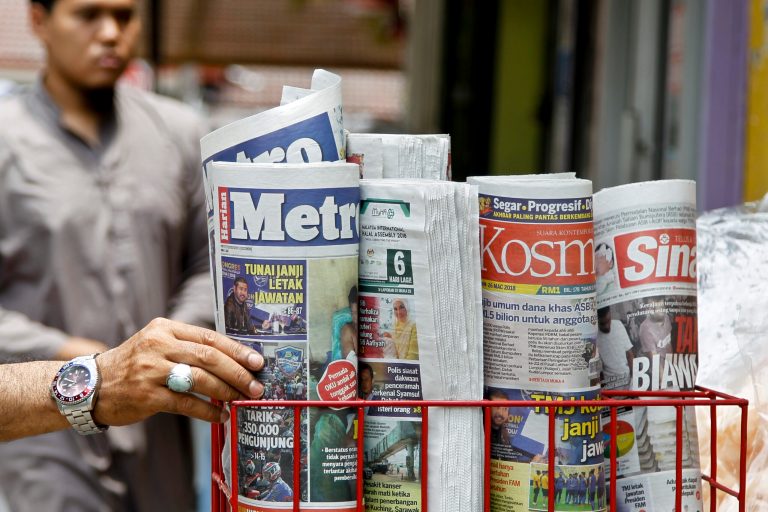 A man takes a copy of newspaper at a grocery shop in Shah Alam, Malaysia, Monday, March 26, 2018.