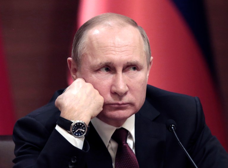Russian President Vladimir Putin listens while attending a news conference.