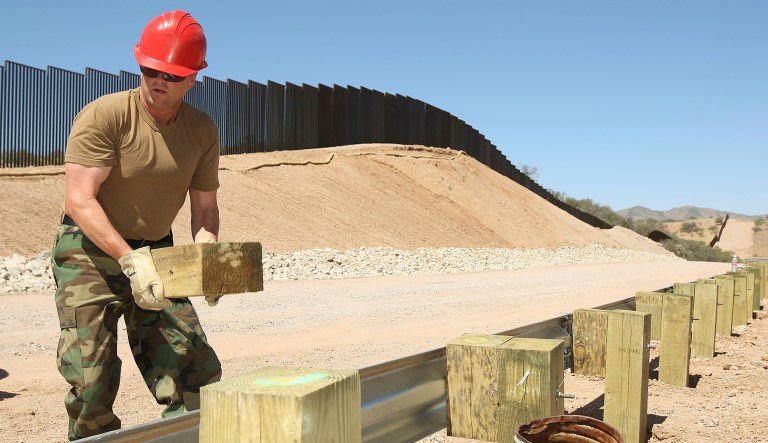 In this June 19, 2008, file photo, in front of a new five-mile section of border fencing, Master Sgt. Ken Clemens, a member of the 200th Red Horse Air National Guard Civil Engineering Squadron from Camp Perry in Ohio, works on a new guardrail along a new road at the border in Nogales, Ariz. 