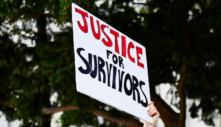 A sign that says "Justice for Survivors" of sexual assault is seen.