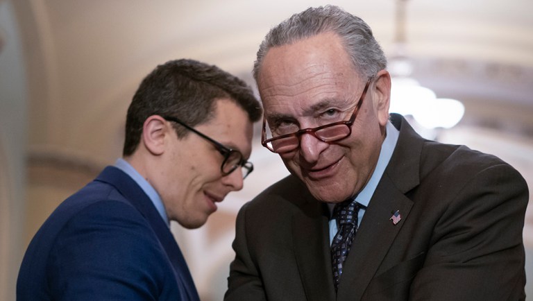 Senate Minority Leader Chuck Schumer, D-N.Y., confers with his communications aide Matt House as he speaks to reporters following a closed-door strategy session.